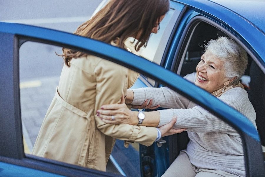 staff person helping senior in car - near u and me